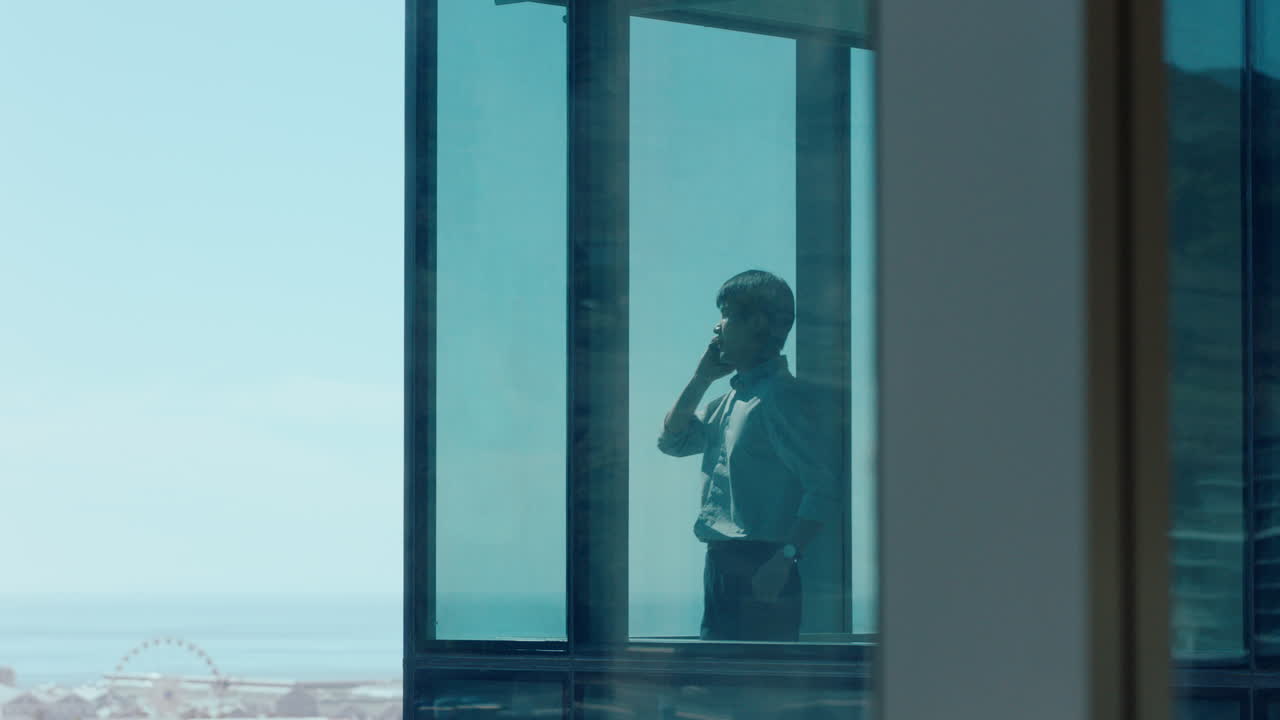 asian businessman using smartphone talking to client corporate executive negotiating deal consultant for sales company having phone call working in office looking out window at city