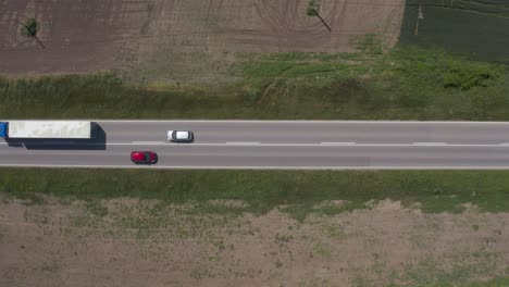 aerial shot of traffic on the road through countryside landscape - trucks and cars on highway