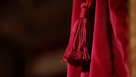 Close-up of a red velvet curtain with a tassel