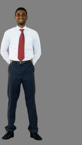 portrait of smiling businessman standing with hands behind back