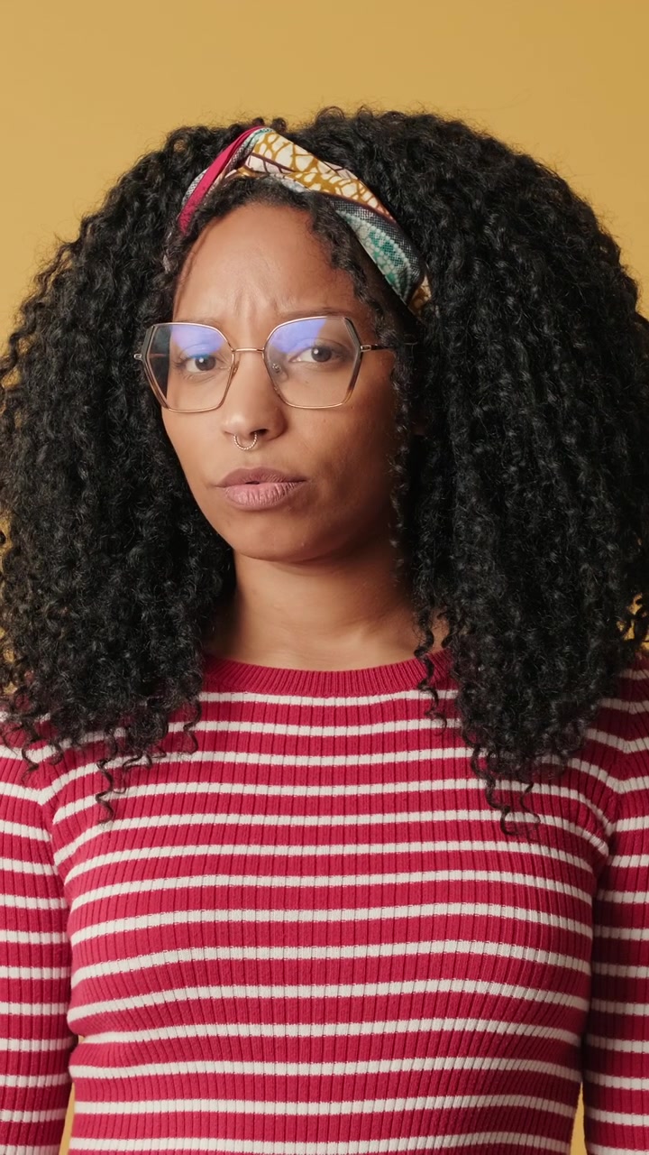 Young Woman With Curly Hair Looking at Camera Against Yellow Background
