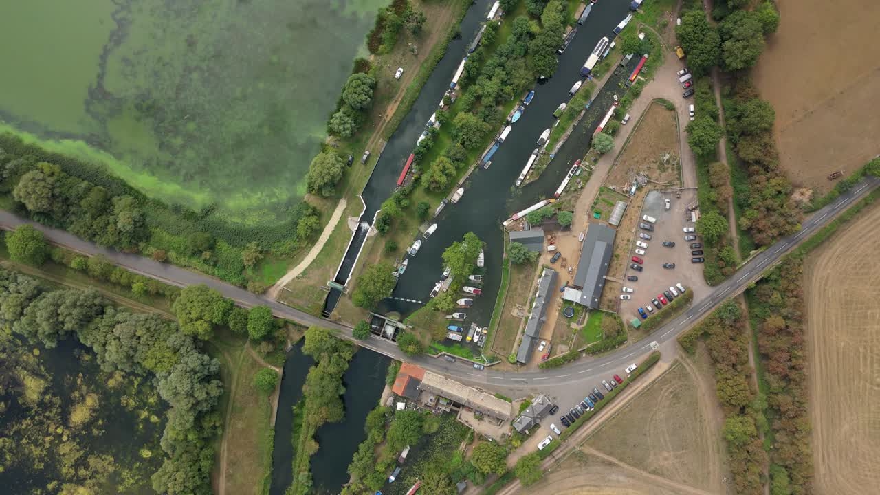 Drone footage of narrow boats and yachts near lock gates on river running through rural Great Addington England UK
