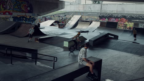 sporty teenagers spending time together at urban skate park with graffiti.