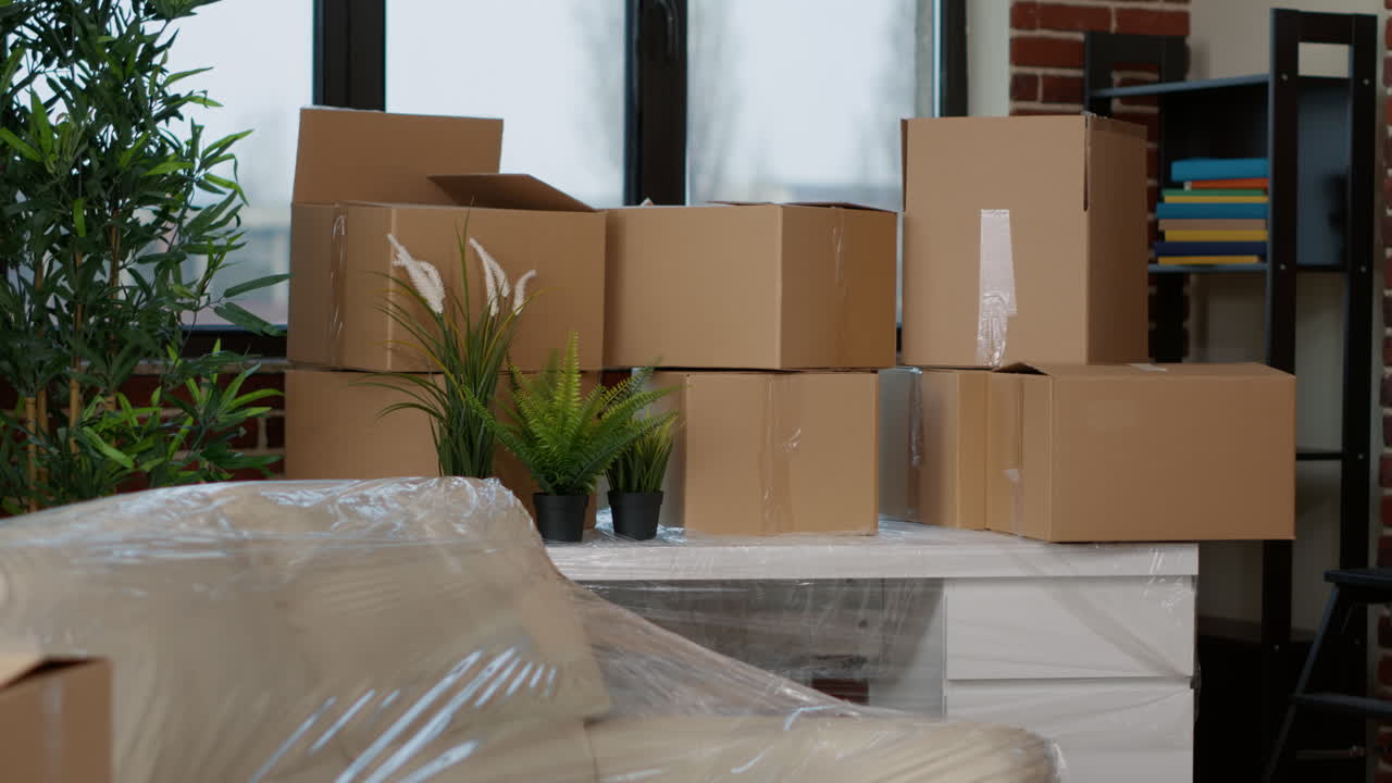 Stacks of moving carton packages on table with plants and decor