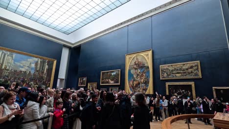 visitors gather around famous paintings in louvre museum