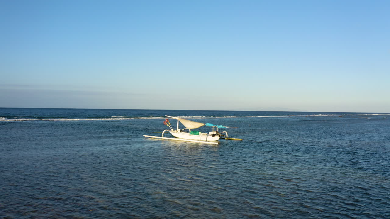 인도양 한가운데에서 놀라운 전통 발리 범선을 포착하기 위해 드론을 포워딩하고 큰 파도가 해안에서 거품을 일으키고 부서지는 모습
