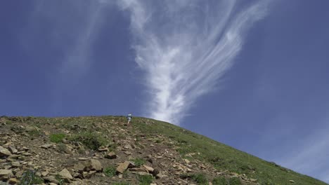 hiker ascending mountain sky clouds rockies kananaskis alberta canada