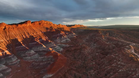 striped sandstone mountains under cloudy sky in utah, usa - aerial drone shot