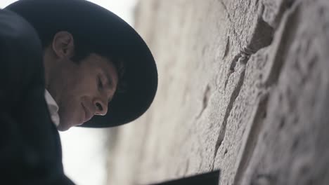 orthodox jewish man with eyes closed praying at wailing wall in jerusalem, israel. low angle shot