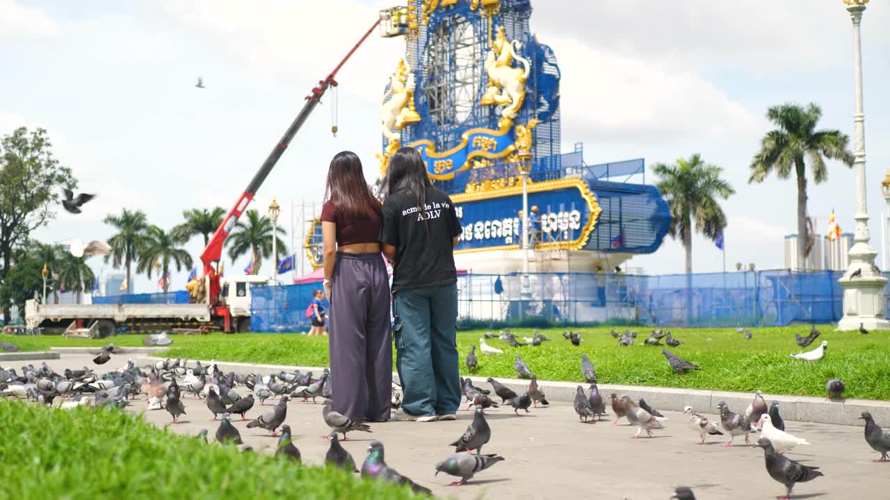 Girls feeding pigeons outdoor, avian birds fly eating breadcrumbs Southeast Asia