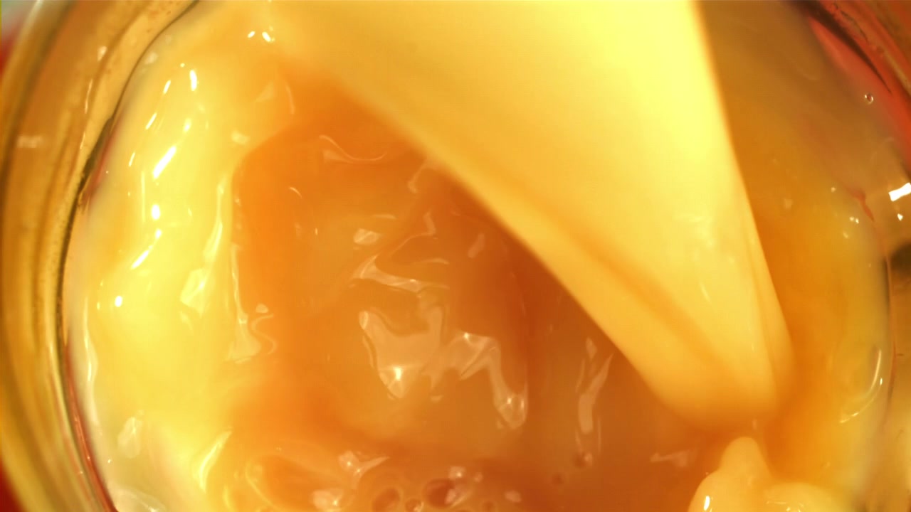 Primo piano di liquido denso e dorato che viene versato con bolle.