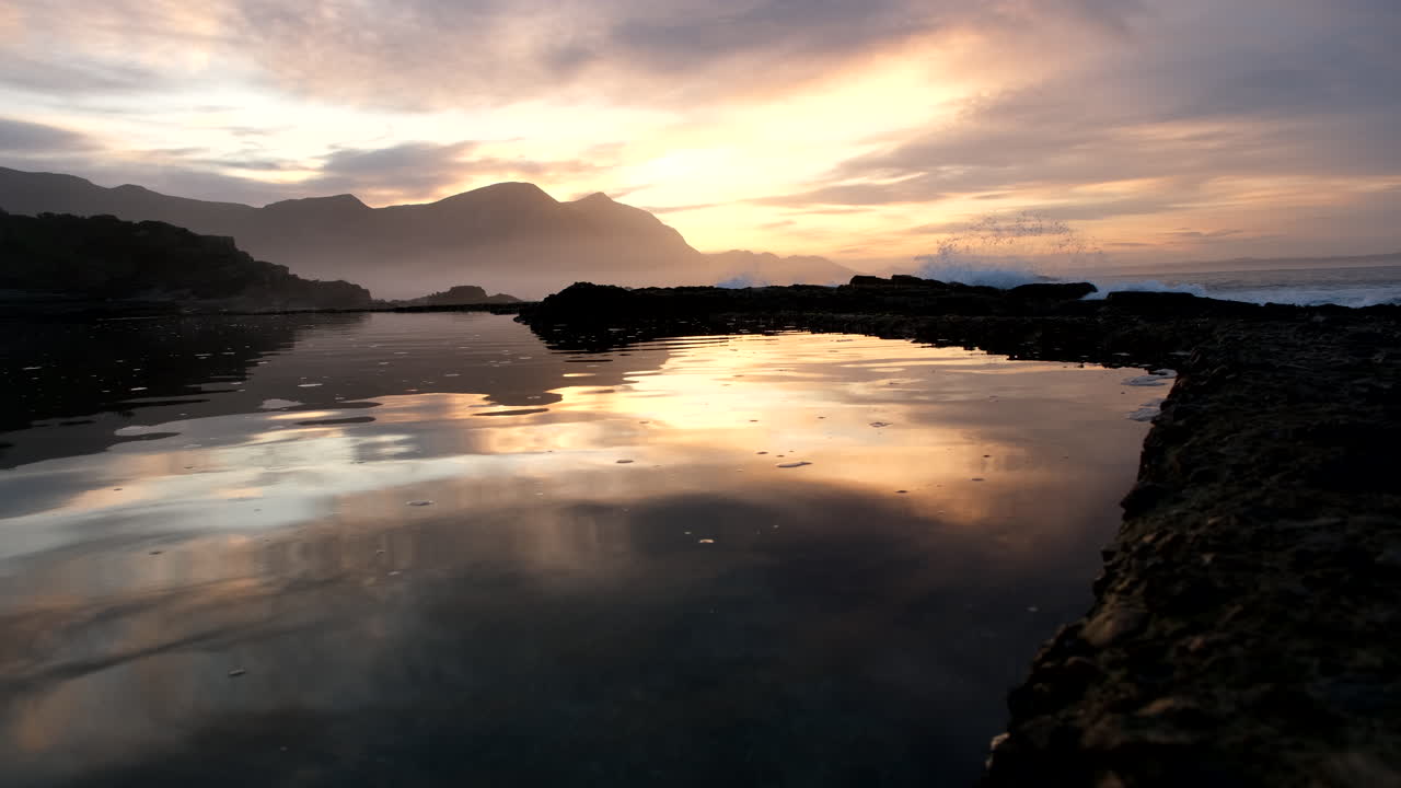 Golden sunrise over Hermanus Walker Bay reflected in Marine Tide Pool, low angle