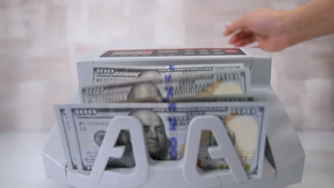 currency counting machine counts dollar bills. money counting equipment for paper money calculation. currency exchange of one hundred dollars. front view.