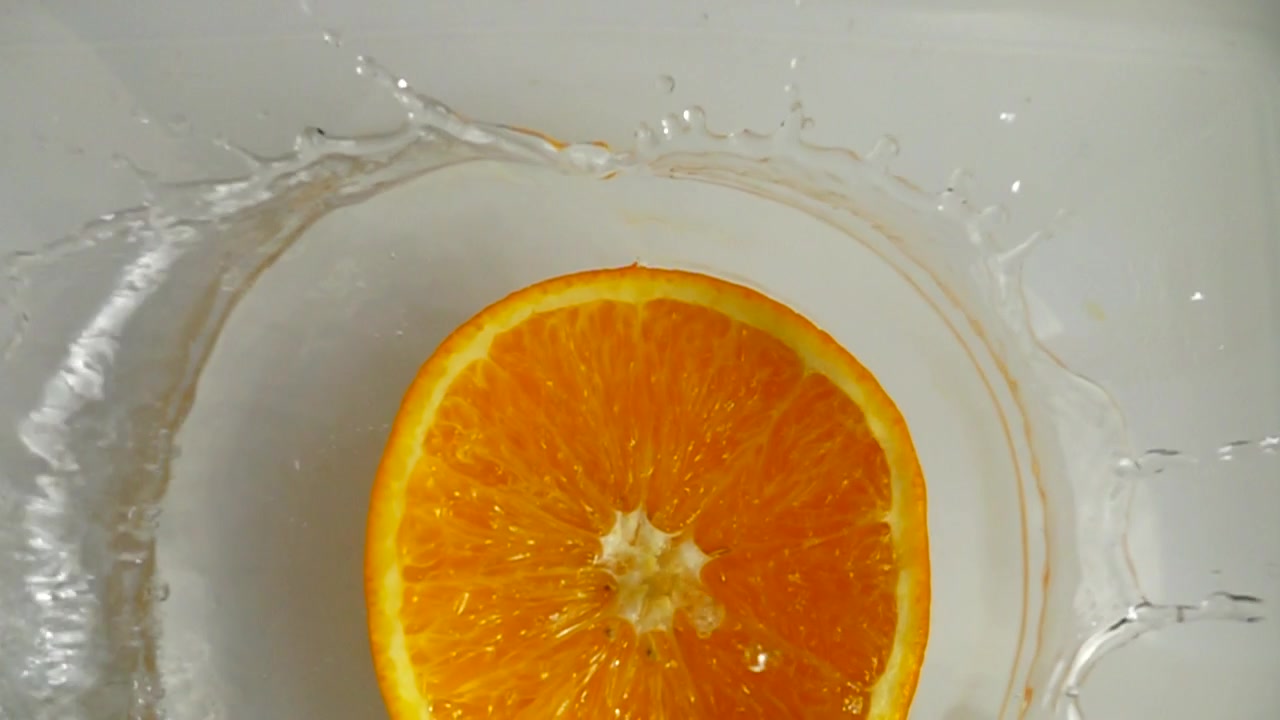 Arance che cadono nell'acqua. Rallentatore.