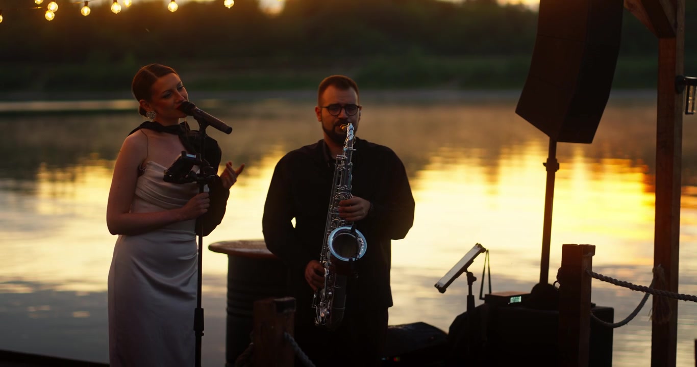 Duo optræder med musik på en mole ved solnedgang.
