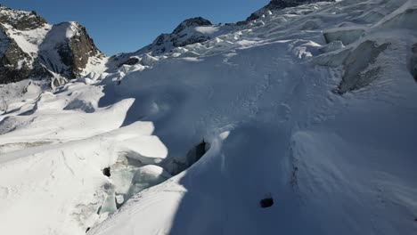 aerial push in: icy peaks and crevasses in a swiss alps glacier in winter