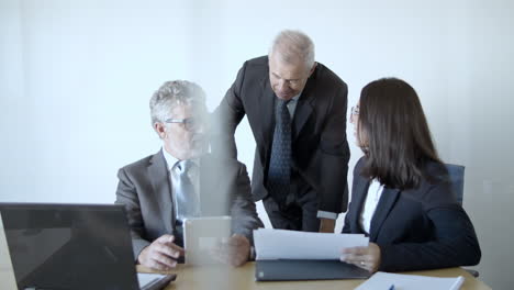 group of businesspeople of different ages talking and studying data