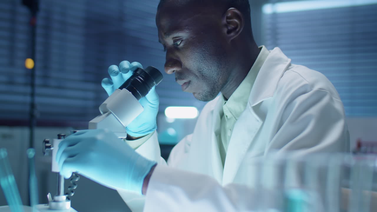 Black Scientist Working with Microscope in Laboratory