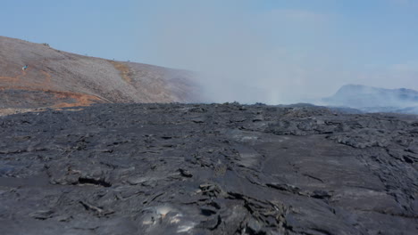 Otherworldly-volcanic-landscape-in-Iceland-Fagradalsfjall.-Aerial-drone-flying-low-above-black-smoky-lava,-dolly-in,-day