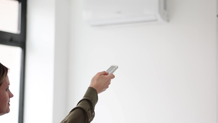 Woman operating air conditioner with remote control