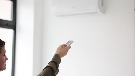 woman operating air conditioner with remote control