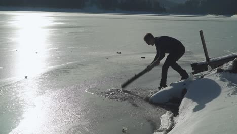 un uomo che rompe il ghiaccio duro nel lago durante il clima estivo