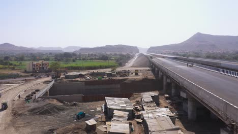 birds flying across the pipeline construction area, beside the road where cars are passing by during a sunny day