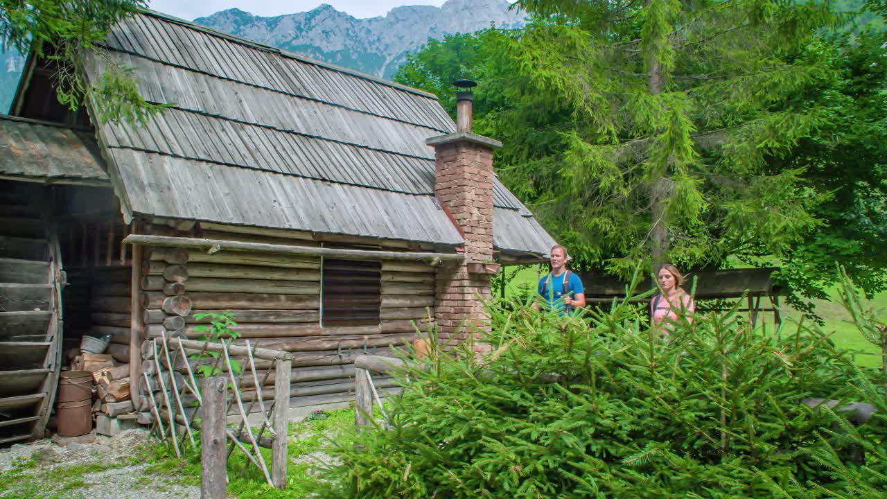 Wide shot of tourists leaving a wooden cabin in the forest and going to do some trekking in Topla Valley in Slovenia