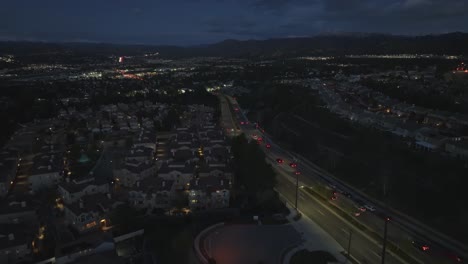 Suburb-residential-neighborhood-at-night-following-traffic-over-houses,-aerial-view