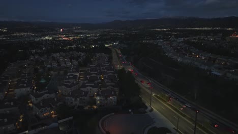 barrio residencial de los suburbios por la noche siguiendo el tráfico sobre las casas, vista aérea