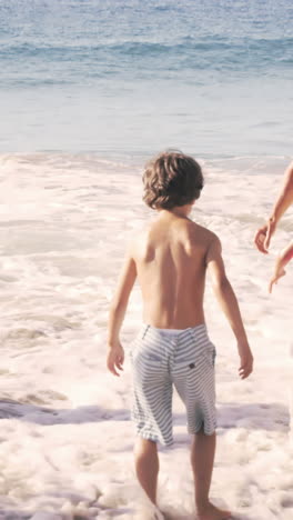 cute family playing with the waves on the beach