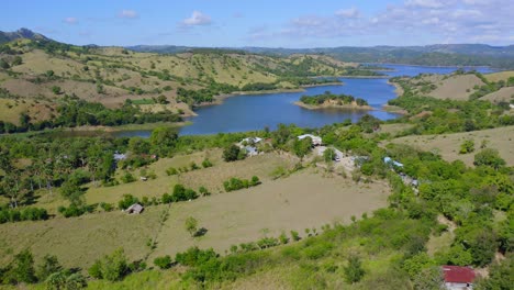 aerial forward over green fields surrounding bao dam in dominican republic