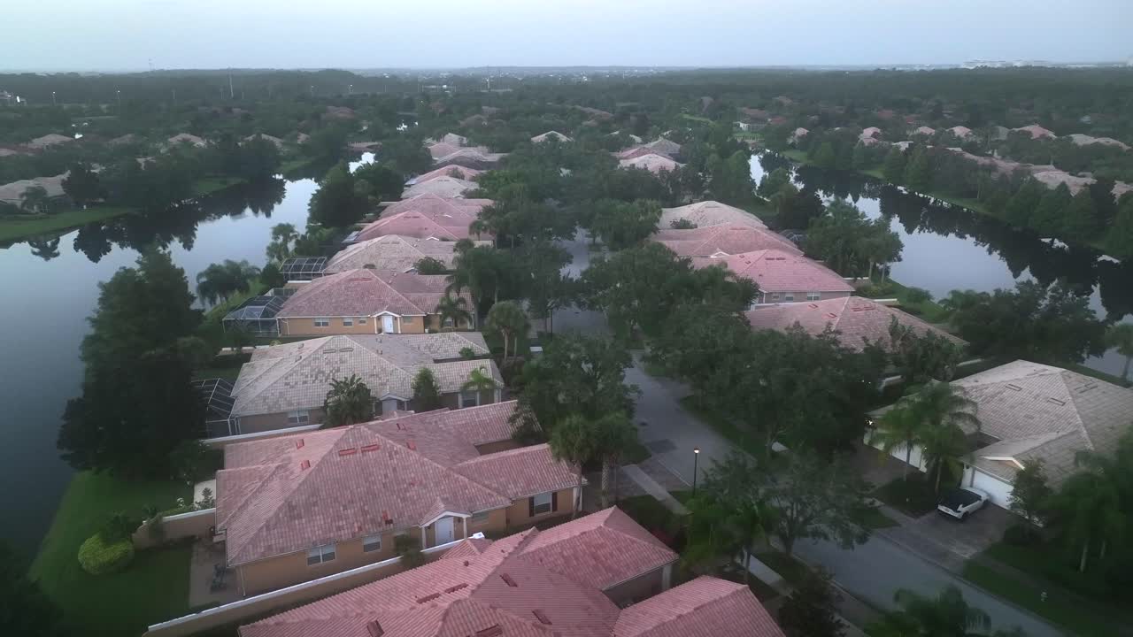 Foggy day in exclusive suburb neighborhood with villas and private river in garden. Aerial approaching shot. Red roofs of one level mansions. Palm trees in Orlando neighborhood. Wide shot