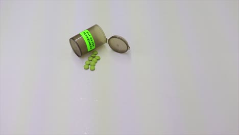 persona recogiendo un arma de fuego negra con una botella de medicamentos de pastillas vacías con un signo de somnolencia de precaución y pastillas al lado del arma de fuego
