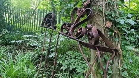 rusty twisted wrought iron gate discarded in dense woodland forest unused and damaged