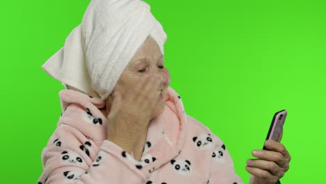 elderly grandmother in bathrobe. old woman using mobile phone for video call