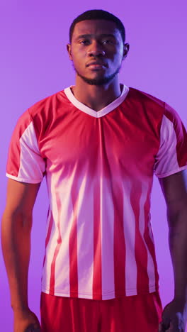 video vertical del retrato de un jugador de fútbol afroamericano sobre iluminación rosada