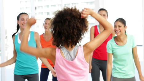 pretty instructor leading zumba class in fitness studio