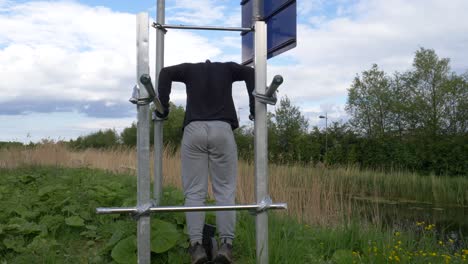 vista trasera del hombre haciendo el ejercicio de tríceps en la barra de bricolaje cuando los gimnasios están cerrados debido a una pandemia en dublín, irlanda - tiro estático