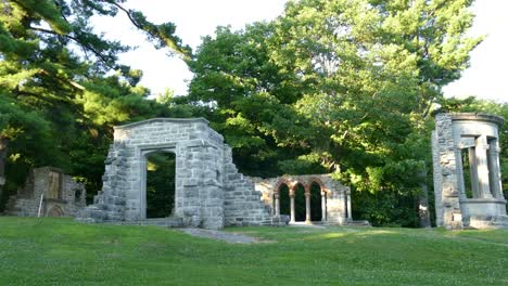 a old stone doorway to a antique place srrounded by tall green tree, static shot