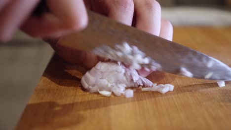 chopping onion with sharp knife on a cut board