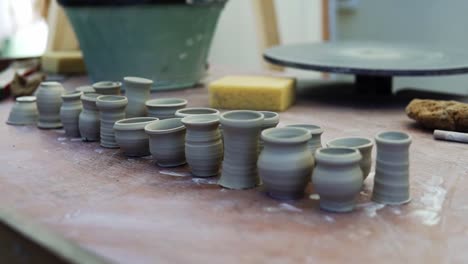 un primer plano de algunas ollas de arcilla cruda colocadas en una mesa afuera para que se sequen bajo la luz del sol