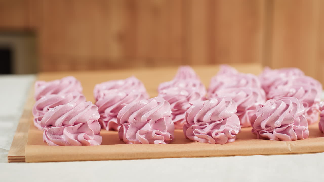 Neatly arranged swirl pink cupcakes sit on brown baking paper in kitchen setting, showcasing delicate frosting texture and perfect shape, ready for baking