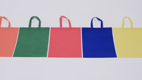 video of row of multi coloured canvas bags with copy space on white background