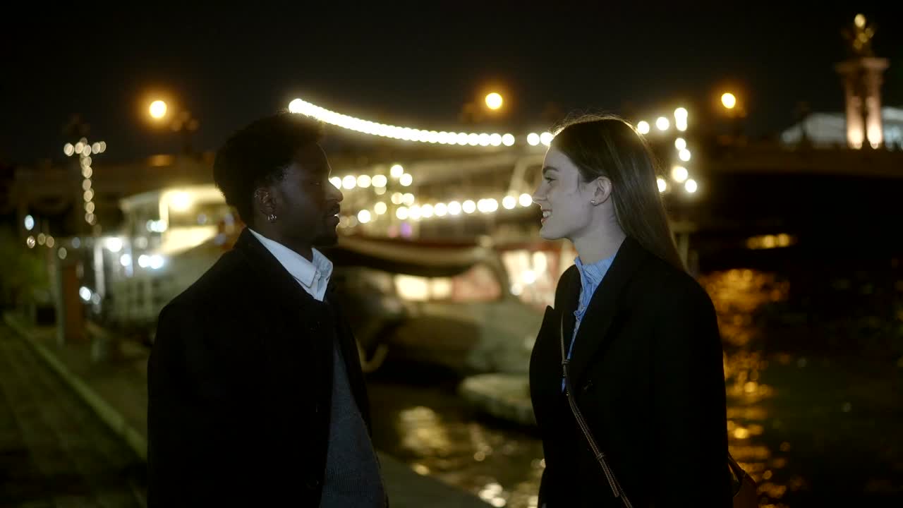 A couple conversing at night in an urban environment