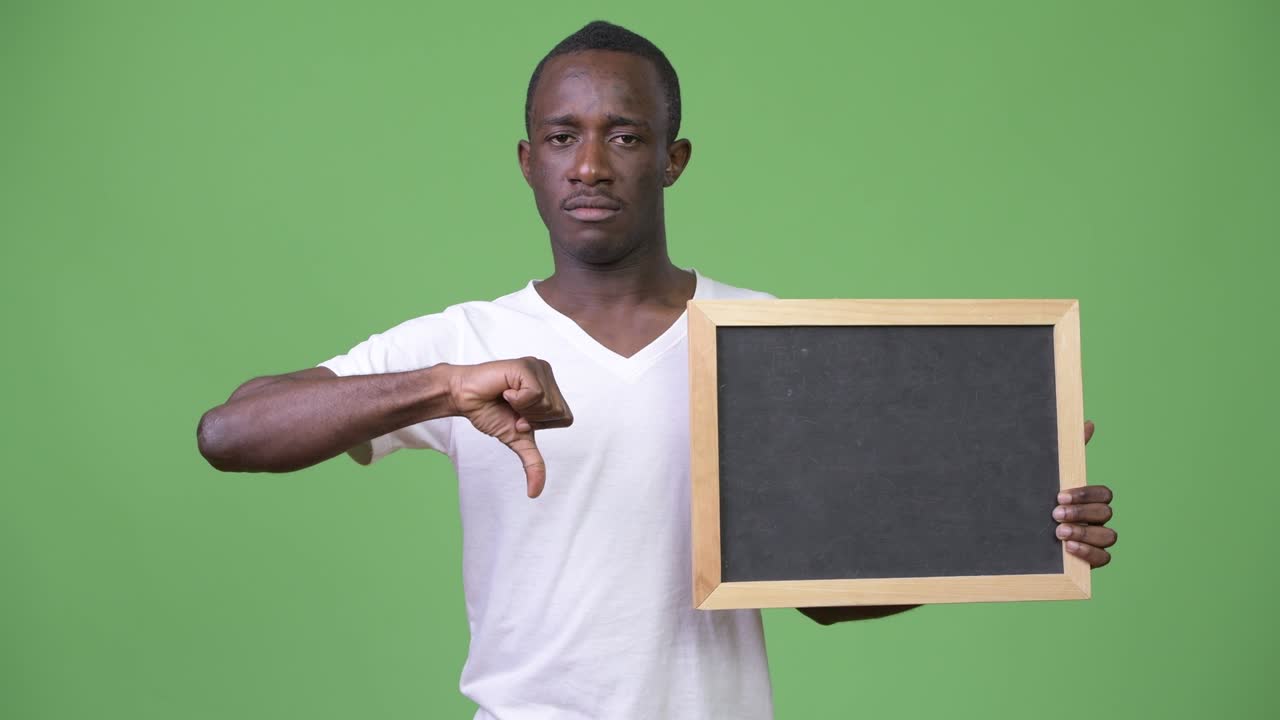 Young African man showing blackboard and giving thumbs down