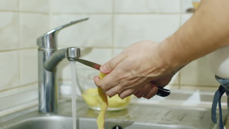 a man in the kitchen peels potatoes