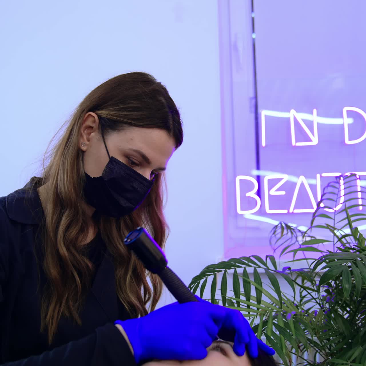 Modern salon procedure for brow tattoo. Female beautician uses special device to perform permanent make up of eyebrows