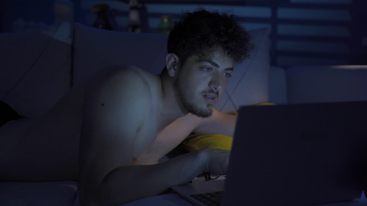 Young man is using laptop at night.