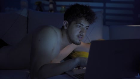 el joven está usando la computadora portátil por la noche.